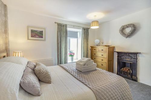een slaapkamer met een groot bed en een open haard bij Smithy Cottage in Bradwell