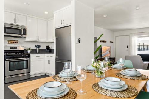 a kitchen with a table with plates and wine glasses at Spacious Coastal Apartment in a Colorful Community - NRP22-00590 in Long Beach