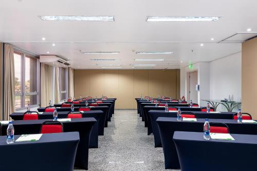 a room with rows of tables and red chairs at Holiday Inn Manaus by IHG in Manaus