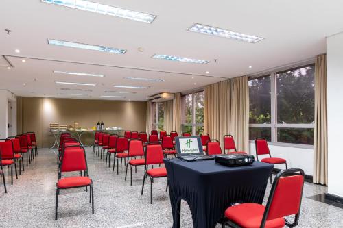 a conference room with red chairs and a table with a laptop at Holiday Inn Manaus by IHG in Manaus