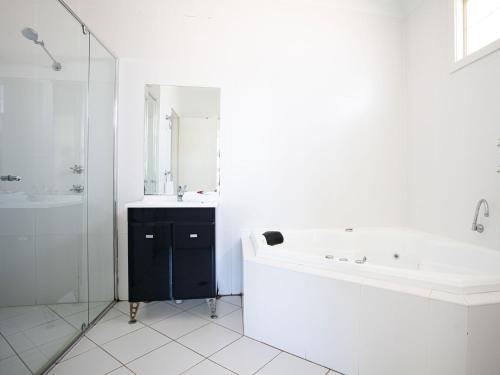 La salle de bains blanche est pourvue d'une baignoire et d'un lavabo. dans l'établissement Mounties @ Sussex, à Sussex Inlet