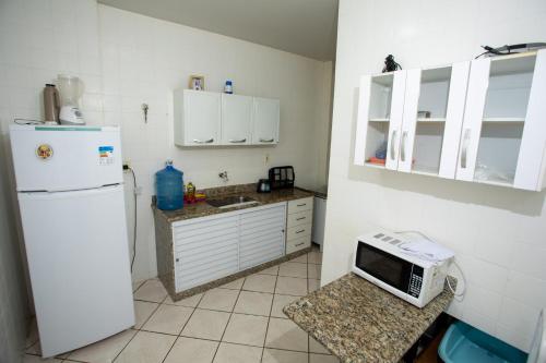uma cozinha com um frigorífico branco e um micro-ondas em PRAIA DO MORRO - APTO 3 QUARTOS SENDO 2 SUITES WIFI 300 MB E GARAGEM - 50 METROS da PRAIA - ATÉ 8 PESSOAS em Guarapari