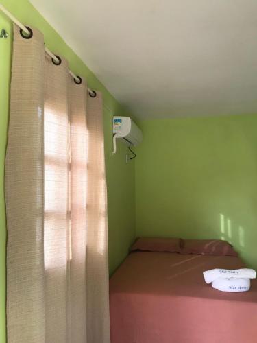 a small room with a bed and a window with curtains at Mar Aberto_chale 3 in Barroquinha