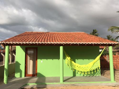 a green building with a red roof and a yellow hammock at Mar Aberto_chale 3 in Barroquinha