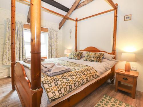 a bedroom with a four poster bed and a window at Bwthyn Alarch in Haverfordwest
