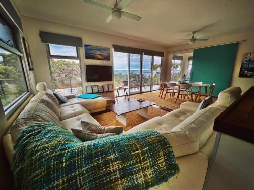 uma sala de estar com um sofá e uma mesa em Sunrise on Falie Seaview Eco Accommodation em American River
