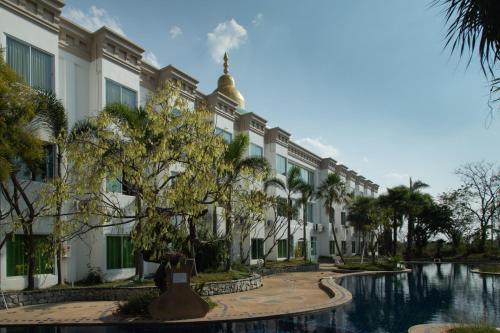 a building with a pool and trees in front of it at Gassan Panorama Golf Club in Ban San Pa Hiang