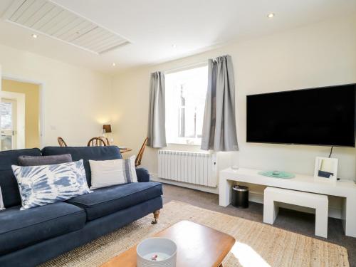 a living room with a blue couch and a flat screen tv at The Bakers Loft in Ambleside