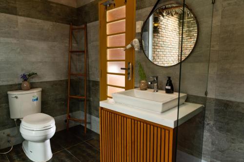 a bathroom with a sink and a toilet and a mirror at Binh Minh Eco Lodge in Can Tho