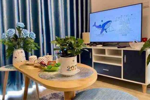 uma sala de estar com uma mesa com televisão e plantas em An Chúc H Homestay 1 Ngủ em HÆ°ng YÃªn