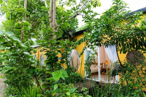 a garden with a yellow house with trees at Binh Minh Eco Lodge in Can Tho