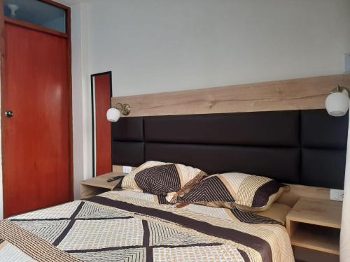 een slaapkamer met een bed met een houten hoofdeinde bij Hospedaje Costa Malabrigo in Puerto Chicama