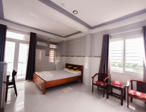 a bedroom with a bed and a desk and windows at NGỌC QUÝ Mini House in Quy Nhon