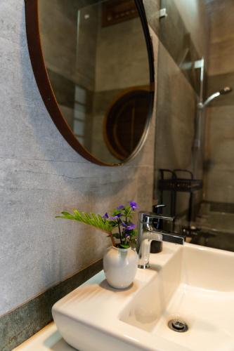 a bathroom sink with a vase with purple flowers in it at Binh Minh Eco Lodge in Can Tho