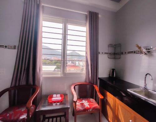 una cucina con due sedie, un lavandino e una finestra di NGỌC QUÝ Mini House a Quy Nhon