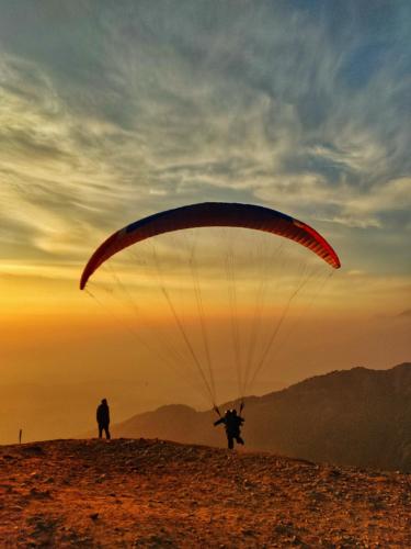 a person flying a parachute on top of a hill at Baseraa - Bir's Hidden Comfort in Bīr