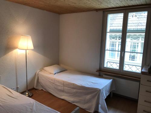 een slaapkamer met 2 bedden, een lamp en een raam bij Simple flat in the centre of Burgdorf - 72 m2 with private parking in Burgdorf