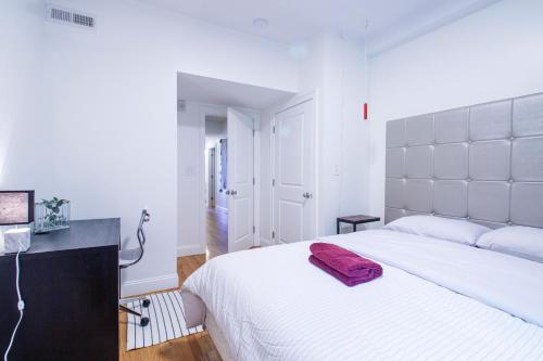 ein Schlafzimmer mit einem großen weißen Bett und einem roten Handtuch darauf in der Unterkunft 3BD 1,5BTH Spacious Apt in Mission Hill in Boston