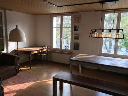 een woonkamer met een tafel, een bureau en ramen bij Simple flat in the centre of Burgdorf - 72 m2 with private parking in Burgdorf