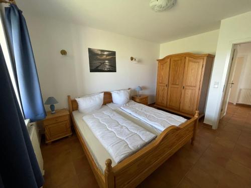 a bedroom with a bed and a wooden cabinet at Windland-Bakenberg in Dranske