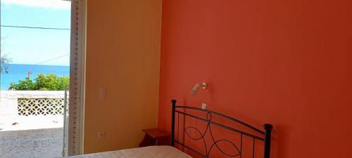 a bedroom with orange walls and a bed and a window at Billy's Amoudi Apartments in Amoudi