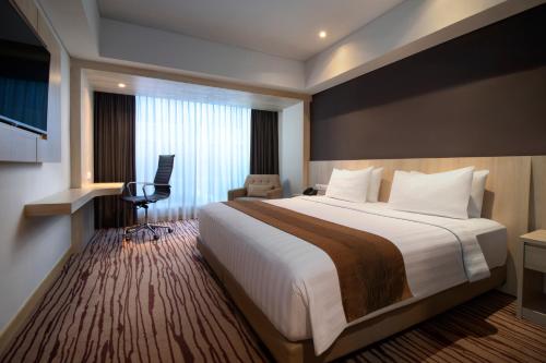 a hotel room with a large bed and a desk at Sovereign Bali Hotel in Kuta