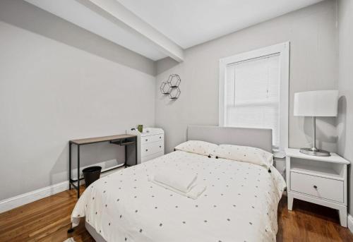 a white bedroom with a bed and a desk at Sunny 4bd 2bth Apt In Somerville in Somerville