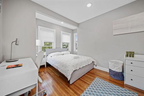 a white bedroom with a bed and a desk at Sunny 4bd 2bth Apt In Somerville in Somerville