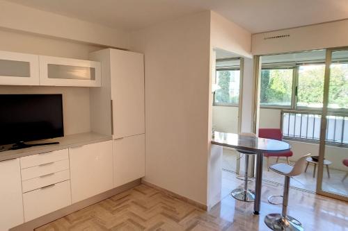un salon avec une télévision, une table et des chaises dans l'établissement HENRI CAMILLE REAL ESTATE - Latour - Studio 150m Martinez, à Cannes