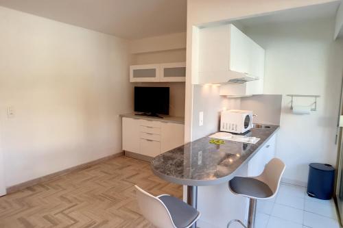 - une cuisine avec un comptoir et des chaises dans la chambre dans l'établissement HENRI CAMILLE REAL ESTATE - Latour - Studio 150m Martinez, à Cannes