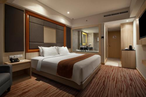 a hotel room with a large bed and a couch at Sovereign Bali Hotel in Kuta