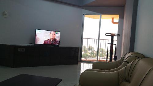 uma sala de estar com uma televisão de ecrã plano e cadeiras em Coastside Homestay em George Town