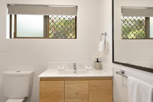 a bathroom with a sink and a toilet and a mirror at Kinka Palms Motel in Yeppoon