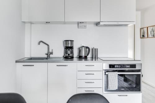 a kitchen with white cabinets and a stove top oven at Lägenhetshotell Varvet in Ellös