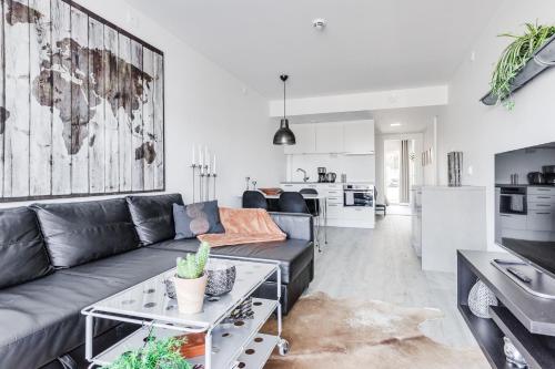 a living room with a gray couch and a kitchen at Lägenhetshotell Varvet in Ellös