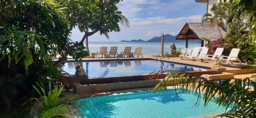 a swimming pool with chairs and the ocean in the background at Papillon Resort in Chaweng