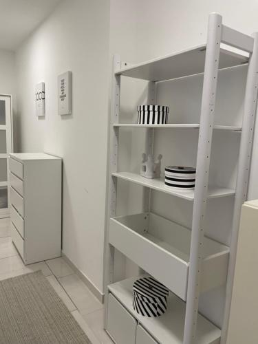 a white book shelf in a room with plates at Stadtsuite mit Sauna in Wiener Neustadt 135 m2 in Wiener Neustadt