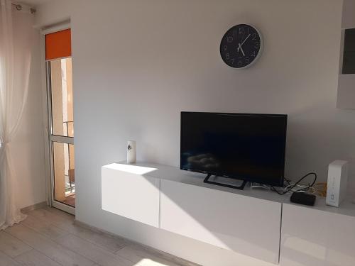 a living room with a tv and a clock on the wall at Apartament w Lądku Zdroju przy Rynku in Lądek-Zdrój