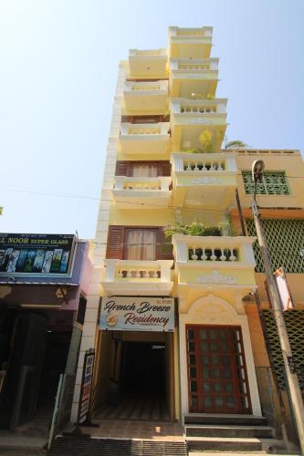 a tall yellow building with a sign on it at French Breeze Residency in Pondicherry