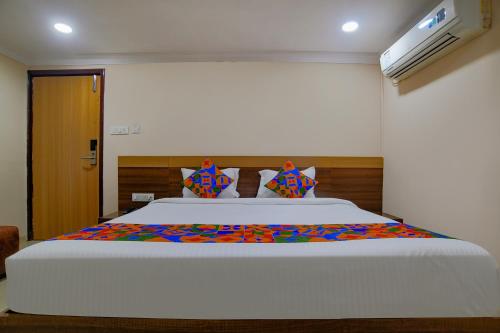 a bedroom with a large white bed with colorful sheets at FabHotel Pishori in Indore