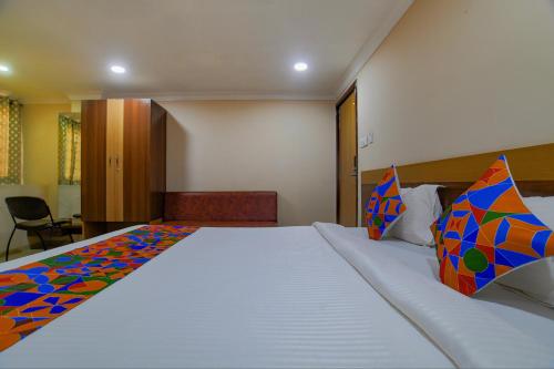 a bedroom with a large white bed with colorful pillows at FabHotel Pishori in Indore