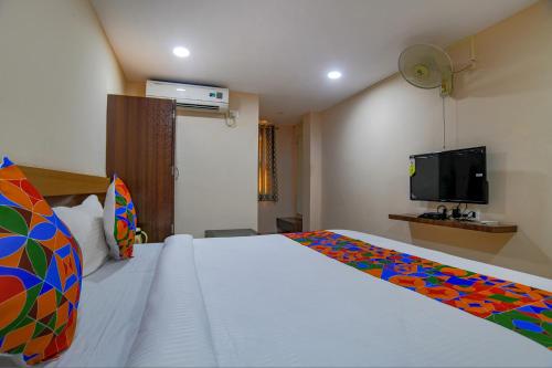 a bedroom with a bed and a tv on the wall at FabHotel Pishori in Indore