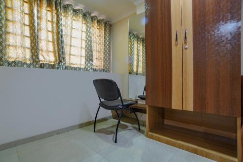 a chair in a room with a desk and window at FabHotel Pishori in Indore