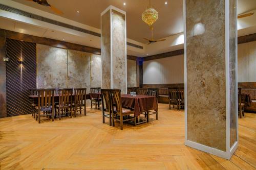 a dining room with tables and chairs and a large mirror at FabHotel Pishori in Indore