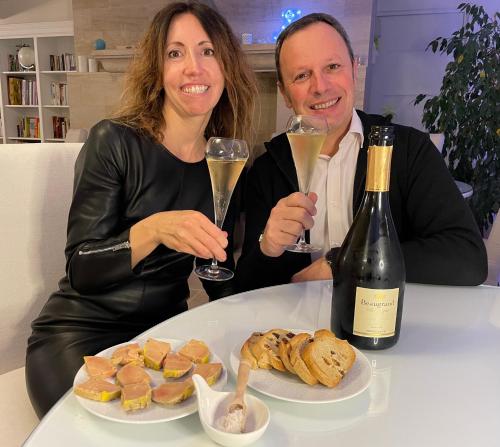 een man en vrouw met een glas wijn en een bord eten bij Villa de la Croix in Villechétif