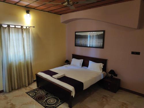 a bedroom with a bed with white sheets and a window at Premier Inn in Yercaud