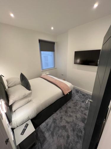 a bedroom with a bed and a flat screen tv at Eden Retreats Serviced Apartments in Morecambe