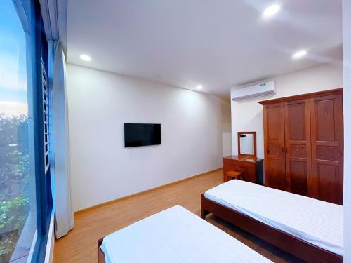 a bedroom with two beds and a tv and a window at Upla Homestay in Vung Tau