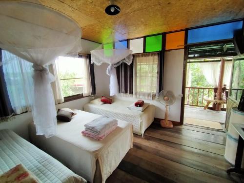 a bedroom with two beds and a room with windows at Metha Country View Homestay Singburi in Ban Kho Sai
