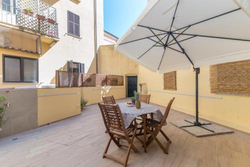 a patio with a table and chairs and an umbrella at Rifla Vacanze in La Maddalena